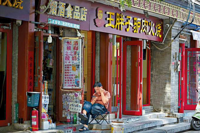 内需有待提升。图为男子坐在北京一间餐厅外。