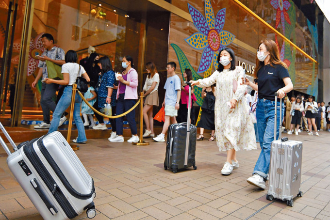 广东道的名牌店外昨日有不少旅客「打蛇饼」，排队等候入内购物。