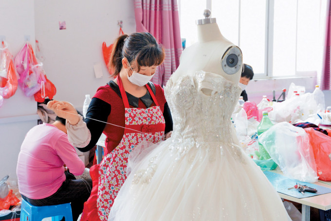 工人在丁集镇婚纱厂内缝制婚纱。