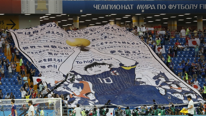 數十名日本球迷在看台上展示了《足球小將》巨型海報，為日本隊打氣。美聯社