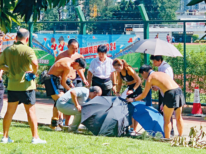 死者在公园跑步径晕倒，多名途人上前协助，有人打开雨伞为他遮荫。