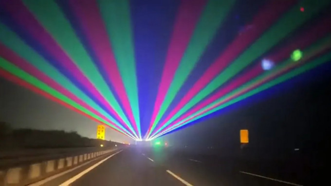 高速公路上几道激光灯射向空中色彩绚丽。
