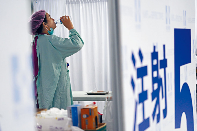 台北一医护人员为民众注射疫苗后，喝水休息。