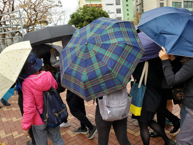 被告在伞阵掩护下离开法院。 资料图片