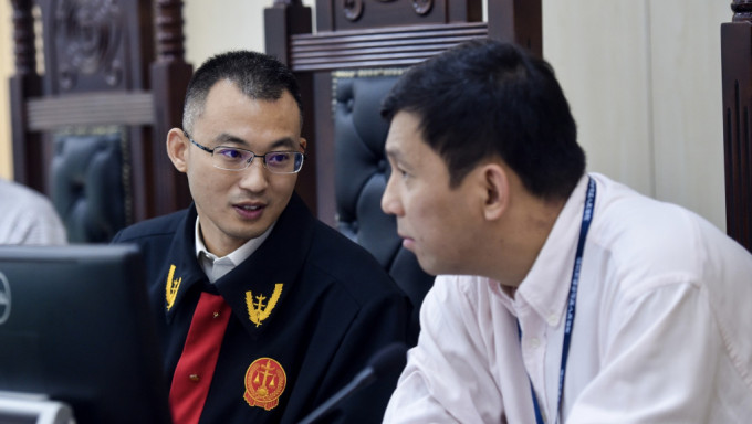 深圳法官（左）在审理破产清算案件过程中与港籍陪审员金孝贤（右）交流。 新华社