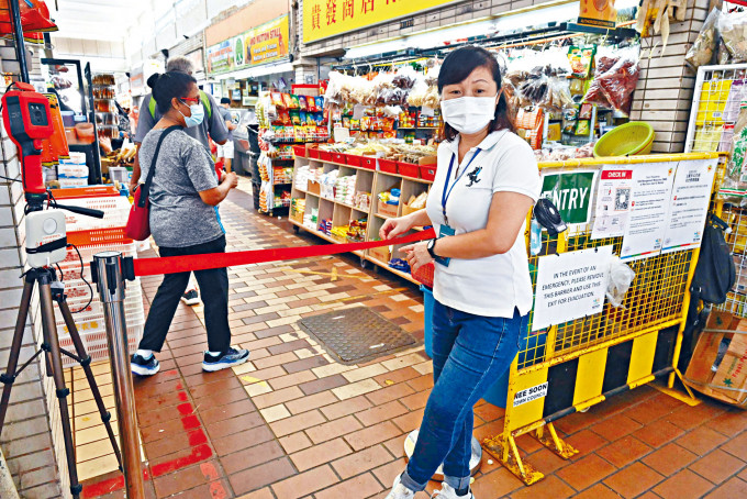 ■新加坡一名工作人員昨天在市場入口控制人流。