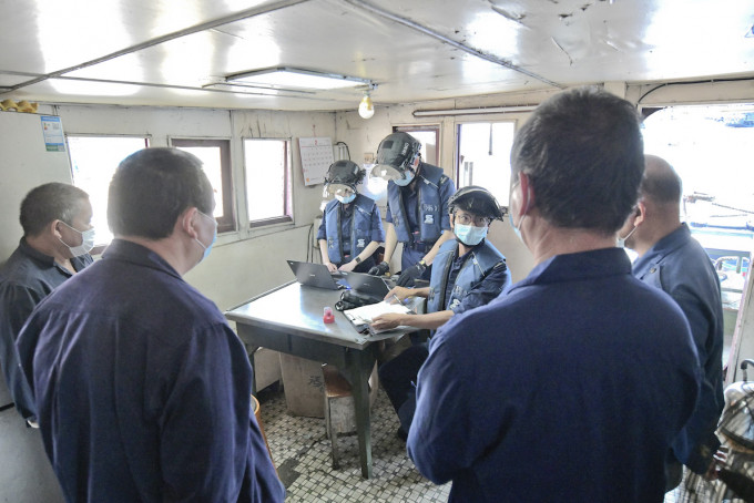 入境處船隻搜查小組多名隊員登上一艘外地躉船，根據申報船員名單逐一檢查，以防有人違法防疫法例偷偷登岸。 梁譽東攝