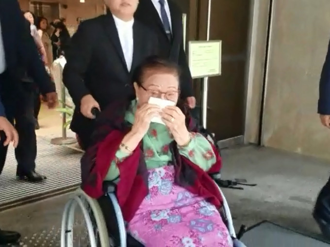 羅老太離開法庭時以紙巾拭淚，隨行的人撫背安慰。影片截圖