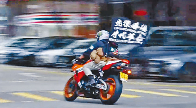 唐英傑當日駕駛電單車，背囊插有「光復香港，時代革命」旗幟。