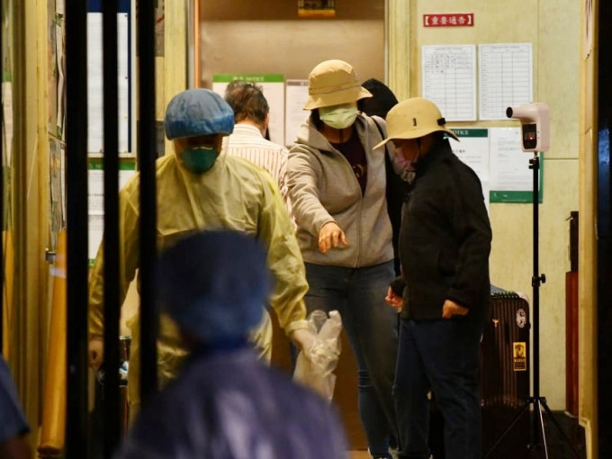 有3名文华阁居民在卫生署职员陪同下拖著行李箱离开。