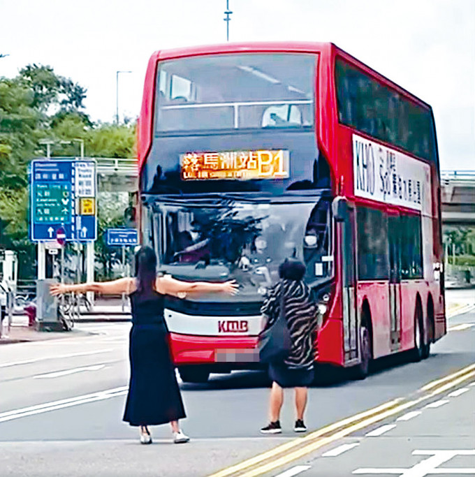 一名女子张开双手站于马路，阻挡巴士去路。