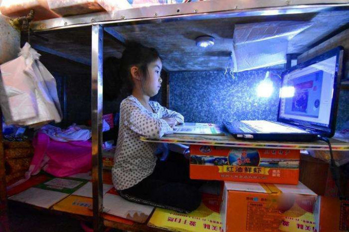湖北7歲女童每天坐攤檔下讀書。(網圖)