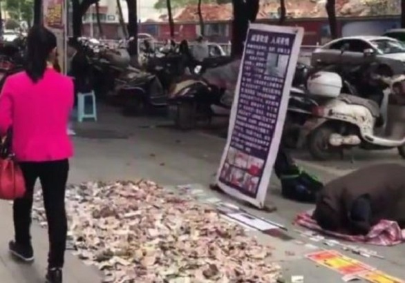 该男子在街头行乞时，从袋中倒出一张又一张钞票，并堆出一座「钞票山」。