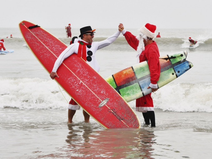 800多名聖誕老人拿起滑浪板在太空海岸滑浪。AP