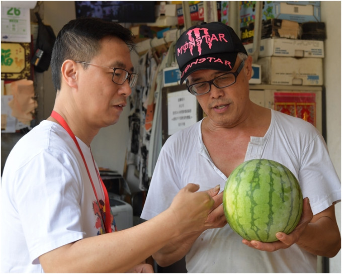 杨润雄（左）到油麻地一间地区小店选购水果。