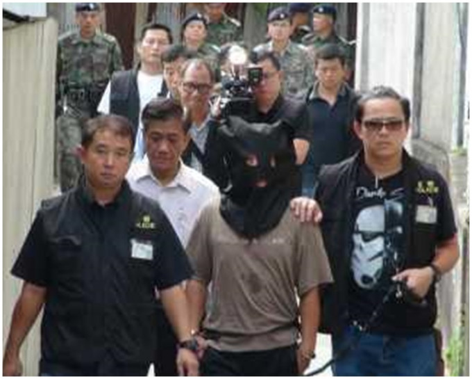 被告阮文强以黑布蒙头由警方带回现场重组案情。资料图片