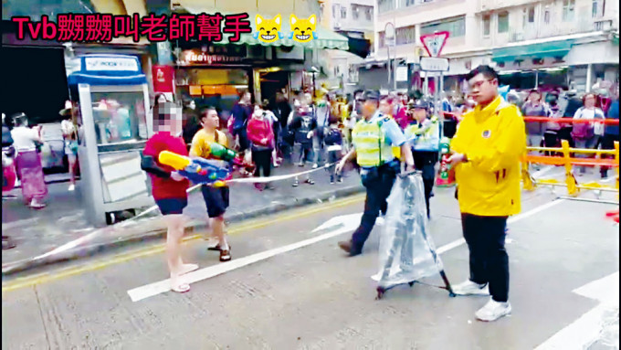 紅衣男子當日以水槍射向TVB記者（右），警員介入。