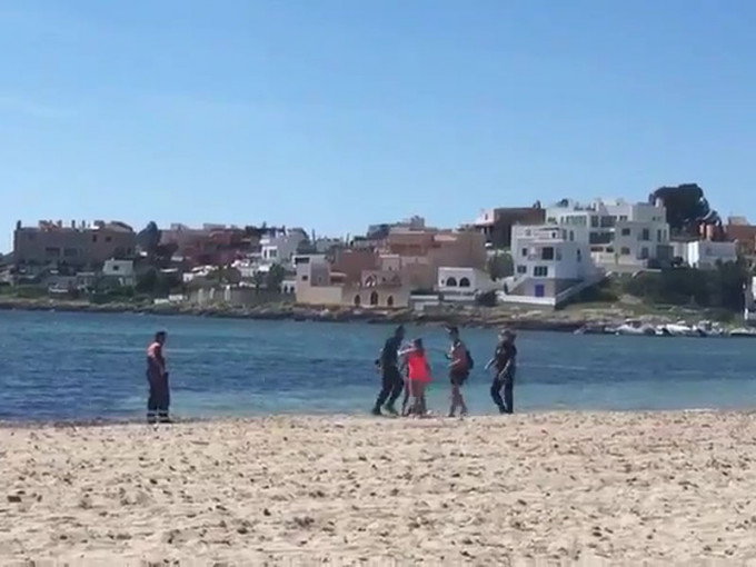 西班牙警察驱赶海滩游客不果，遇反抗被推进海里。(网图)