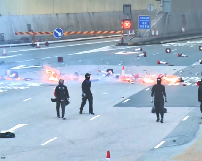 蒙面黑衣人在红隧九龙入口焚烧杂物。港台新闻截图