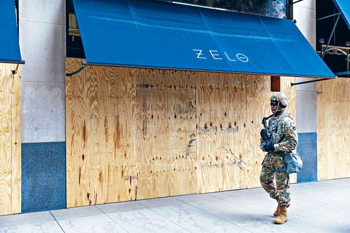 明尼阿波利斯市国民警衞军在一间封上木板的店铺外巡逻。　