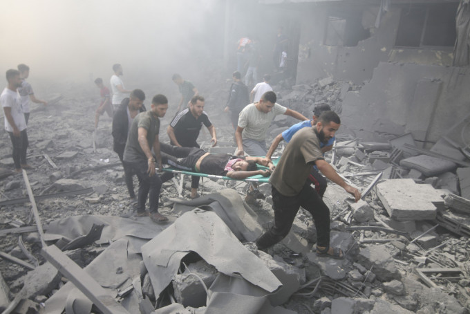 以色列空袭加沙后，当地巴勒斯坦人抬走伤者。美联社
