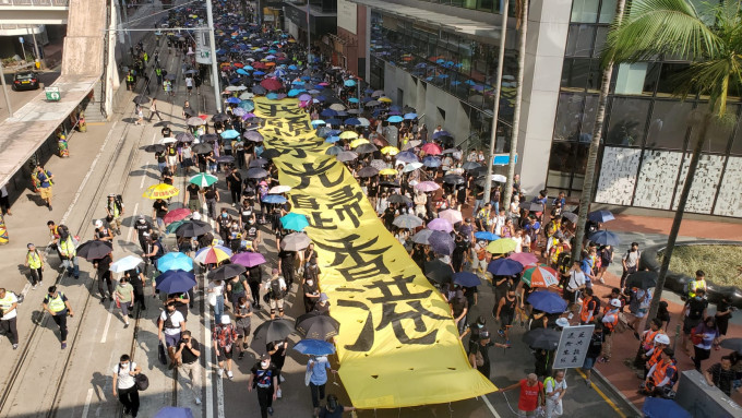 示威者拉起黃底黑字的巨型直幡，沿途高喊口號。