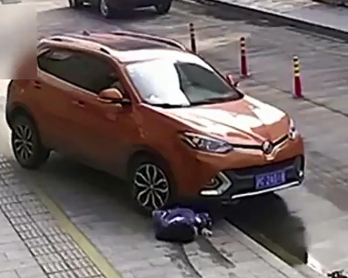 杭州一名女子蹲在車前看手機被捲入車底，險象環生。影片截圖