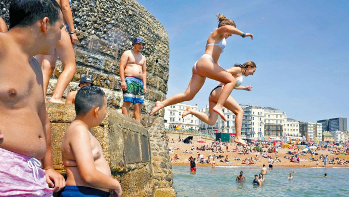 在酷热天气下，英格兰南部布赖顿的居民跳下海中消暑。