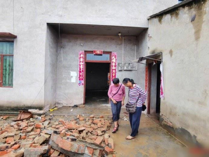 代妻（右）与朋友看着门口的瓦砾。互联网图片