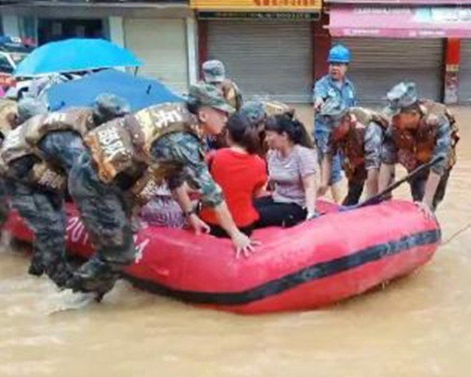 救援人員用橡皮艇將被困居民救出。網圖