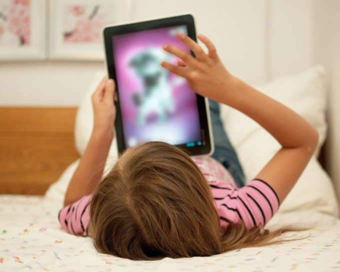 女童每日用平版电脑万游戏或看卡通片，一次玩4至5小时。示意图。