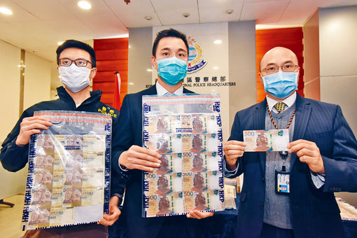 总督察杨新邦（中）展示缉获的伪钞，邓舜仁（右）则手持真钞对比。