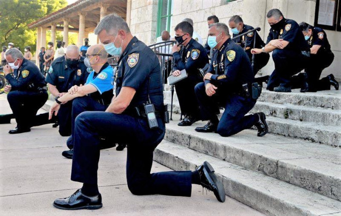 警员单膝下跪悼念死者。网图