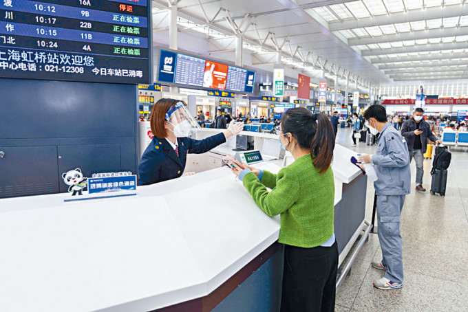 上海虹橋火車站工作人員解答旅客的問詢。