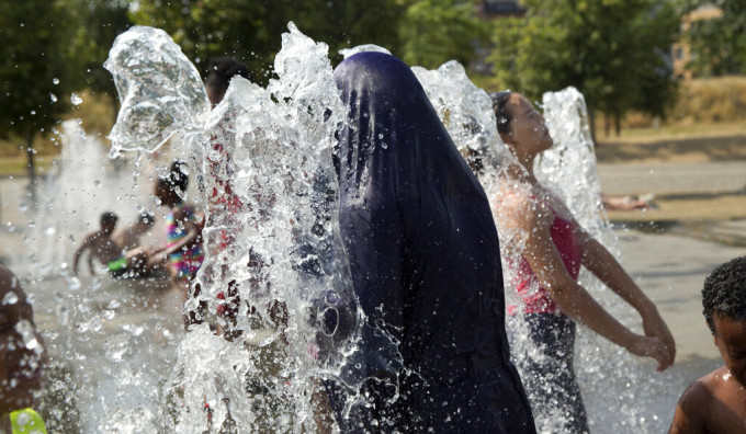 热浪袭欧洲，不少市民于喷泉中消暑。AP图