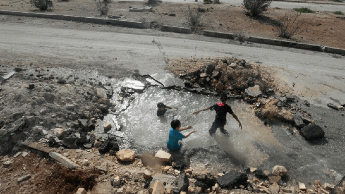 叙利亚儿童利用炸弹坑作泳池，苦中作乐。（路透社）