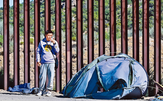 一名中國移民6月5日在美墨邊境牆旁使用手機。
