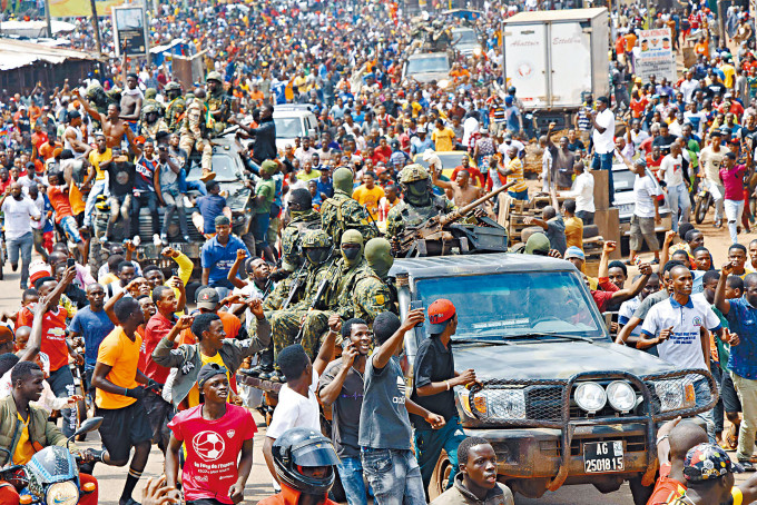 畿內亞叛軍周日宣布推翻總統孔戴後，民眾伴隨軍車在首都街頭慶祝。　