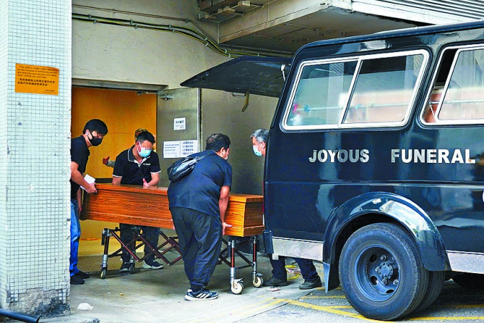 伊利沙伯醫院殮房外，工作人員將棺木抬上殯儀館車輛。