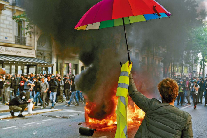 周日巴黎有示威者舉起雨傘和黃背心。