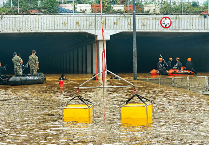 救援人员周日在清州市被洪水淹没的行车隧道的入口，搜索生还者。