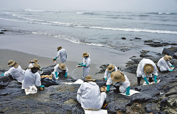 秘鲁工人在海滩清理油污。