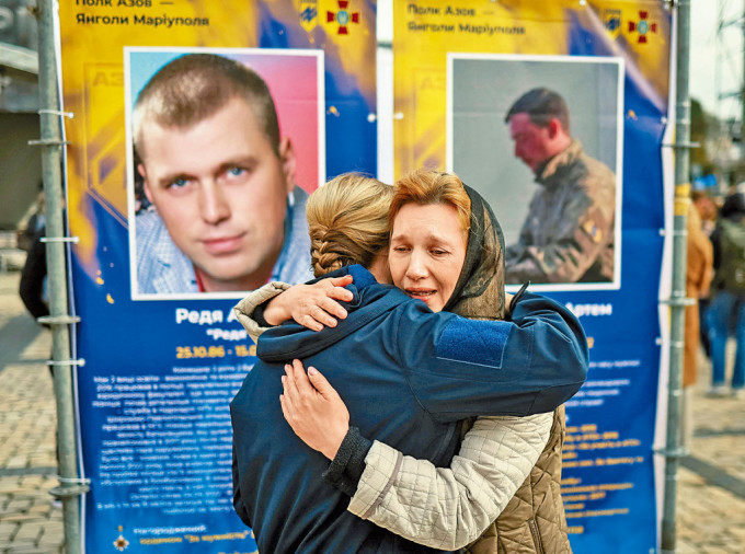 基輔周五舉行保衞烏克蘭日活動，兩名親屬在亞速營陣亡者照片前互擁。
