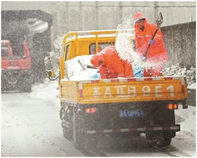 市政人員冒雪在各主要路段拋撒融雪鹽。