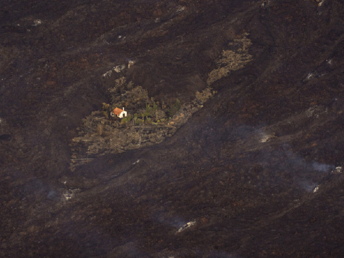 西班牙的奇迹之屋经历火山爆发后仍然屹立不倒，可见其附近的土地仍在冒烟。（美联社）