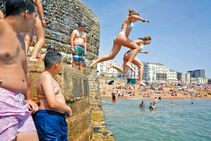 在酷热天气下，英格兰南部布赖顿的居民跳下海中消暑。
