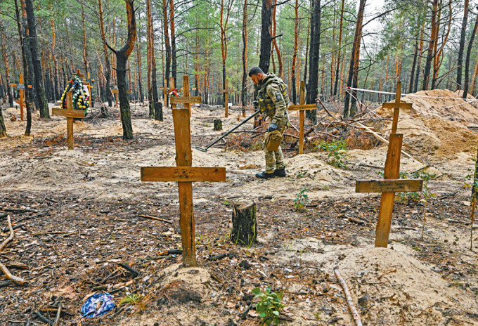 烏克蘭工程人員在伊久姆森林的亂葬崗掃雷。　
