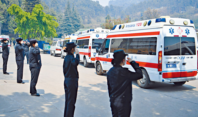 女警向運送十九名殉職撲火人員遺體的車隊敬禮。