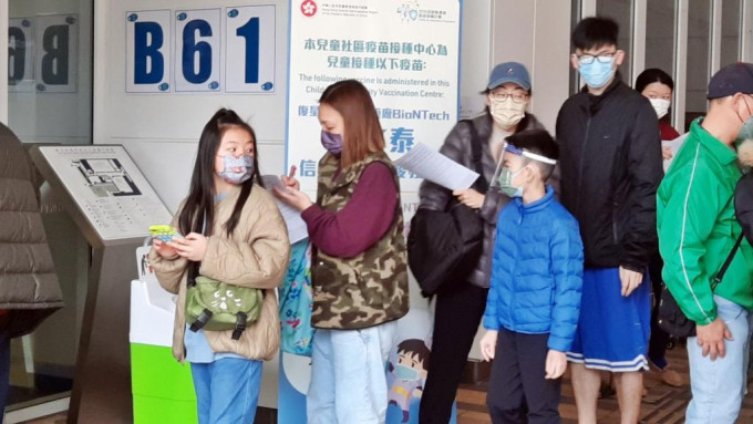 有家長帶同子女到沙田圓洲角體育館兒童社區疫苗接種中心打針。