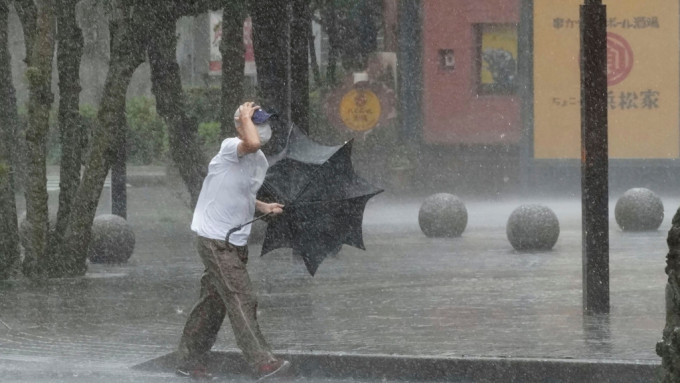 静冈县一名男子在大风大雨中前行。AP